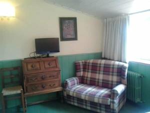 sala de estar con silla y tocador con TV en Hotel restaurant Xalet la Coromina, en Viladrau