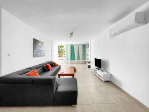 a living room with a black couch and a tv at Elegant Beachside Apartment in Herzliya B