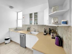 a white kitchen with white cabinets and a sink at Elegant Beachside Apartment in Herzliyya B