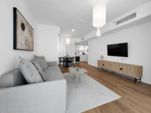 a white living room with a couch and a tv at Ritzside Marina Stay in Herzliya B
