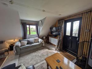a living room with a couch and a tv at The Loft at Rowantree Cottage in Dromara