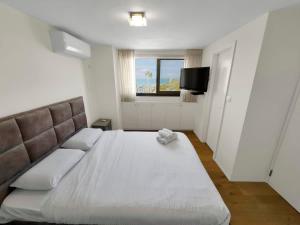 a bedroom with a large white bed and a window at Beachfront Heights Duplex in Herzliya B