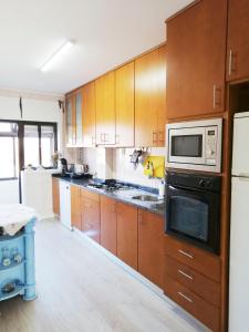 a kitchen with wooden cabinets and a microwave at Ferreirinhas - Beach House in Vila do Conde