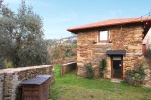 ein Steinhaus mit einer Steinmauer daneben in der Unterkunft Casas de Xisto in Raiva