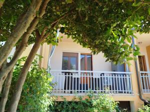 a house with a white balcony and trees at Posidonia Guest House La Caletta Sardegna in La Caletta