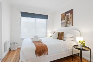 a white bedroom with a large bed and a window at Chic Murrumbeena Retreat in Murrumbeena