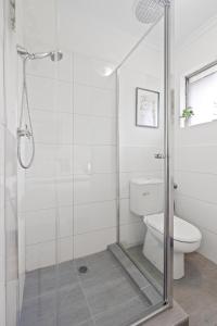 a bathroom with a toilet and a glass shower stall at Chic Murrumbeena Retreat in Murrumbeena +11 photos