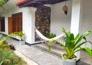 a hammock on the porch of a house with plants at Kalavida - 2 Mins walk to Kabalana Beach in Piyadigama