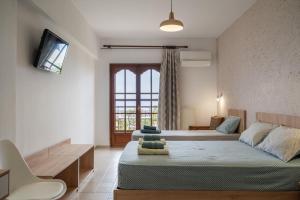 a bedroom with two beds and a couch and a tv at House Mistral in Neos Marmaras