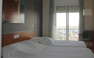 Cama en habitación de hotel con ventana en Hotel Roca Plana, en L'Ampolla