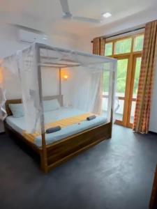 a bed with a canopy in a room with a window at Casa Lashmika in Hikkaduwa