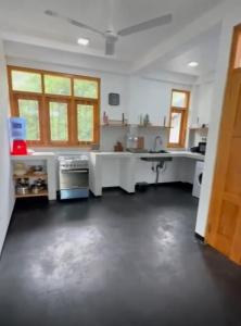 a large kitchen with white counters and a table at Casa Lashmika in Hikkaduwa