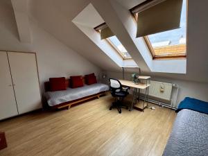 Cette chambre mansardée comprend un lit, un bureau et une fenêtre. dans l'établissement 120 m2 apartment in the centre of the old town, à Bratislava