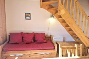 un canapé avec des coussins rouges assis sous un escalier dans l'établissement Votre Havre de Paix en Montagne - chalet 6 personnes avec piscine et sauna, à La Féclaz