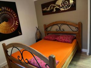 a bedroom with a wooden bed with an orange bedspread at Villa dans la forêt provençale in Jouques