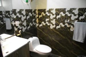 La salle de bains est pourvue de toilettes et d'un mur à motifs. dans l'établissement Luxury 2-BHK Apartment, à Islamabad 14 autres photos