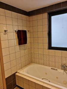 a bath tub in a bathroom with a window at Schinias Hill Mike's Appartments in Panayía Mesosporítissa +30 photos