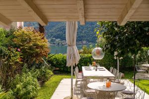 莫尔科泰Gritti Palace Morcote - Waterfront studio with panoramic lake views - Fiordaliso的带桌椅和遮阳伞的露台