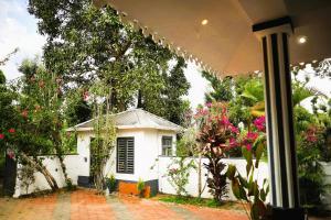a small white house with flowers in front of it at Jungle Tusker Resort The Nilgiris in Pandalūr