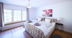 a white bedroom with a large bed and two windows at Design Apartments Schloss Burg Solingen - BRIGHT Collection in Solingen +43 photos