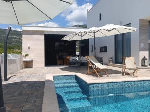 a swimming pool with two chairs and an umbrella at Villa Lauvi, Free Fiat 500 Cabriolet, Scooters , PS5 in Kaštela