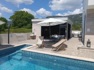 a pool with two chairs and an umbrella next to it at Villa Lauvi, Free Fiat 500 Cabriolet, Scooters , PS5 in Kaštela