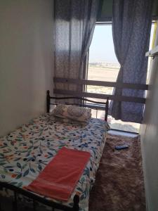 1 dormitorio con 1 cama con ventana y manta roja en The Serene Spot, en Abu Dabi