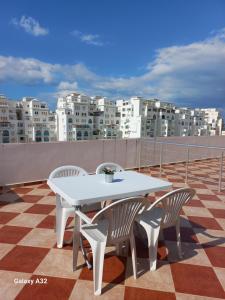 a white table and chairs on a balcony with buildings at Rimal Costa Martil in Martil