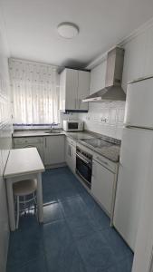 a kitchen with white cabinets and a table and a refrigerator at IAROS Pueblo del Sol T1 in Mogro
