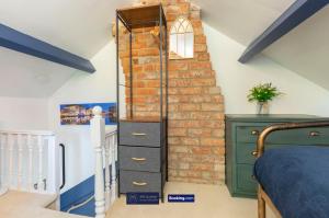 Schlafzimmer mit Ziegelwand neben einem Bett in der Unterkunft Pet Friendly Cottage By KBS Stayhub Short Lets & Serviced Accommodation Stonehouse With Log Fire, Parking in Gloucestershire + 35 Fotos