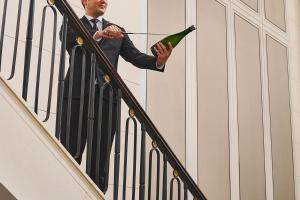 a man in a suit holding a bottle of wine at The St. Regis Singapore in Singapore