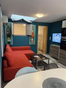 a living room with a red couch and a tv at Gîte à la ferme avec piscine in Urgosse