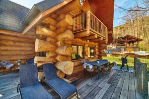 a log cabin with a deck with a table and chairs at Zrub Ontario, Tále in Horná Lehota