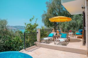 a patio with chairs and an umbrella and a pool at Villa Mandalina, Cukurbag Peninsula-Kas in Kaş