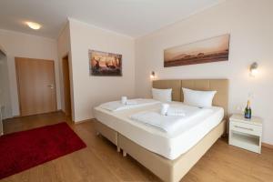a bedroom with a large white bed and a red rug at Kraichgauhotel in Kraichtal