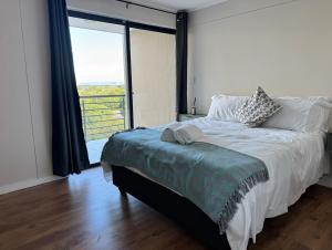 a bedroom with a bed with a large window at Sea facing apartment in Hout Bay