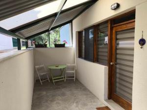 a balcony with a table and chairs and a window at Coralia's House in Nea Moudania