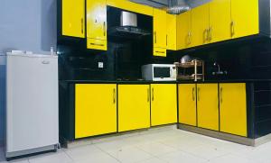 cocina con armarios amarillos y nevera blanca en Luxury apartment at bahria town, en Rawalpindi
