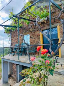 a stone house with a wooden deck and flowers at Quinta de Canelas in Torre de Moncorvo