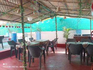 a restaurant with tables and chairs and a blue wall at Helix Guest House in Mandrem