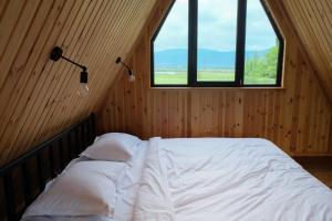 a bedroom with a bed in a room with two windows at Tserovani Velada & Cottages in Mtskheta