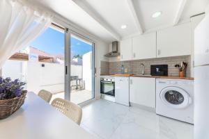 une cuisine avec des appareils blancs et une table avec des chaises dans l'établissement PETRA, à Dénia 17 autres photos