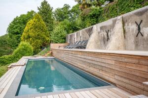 a swimming pool next to a wooden retaining wall at Élégante longère, piscine entre Tours et Amboise in Vernou-sur-Brenne