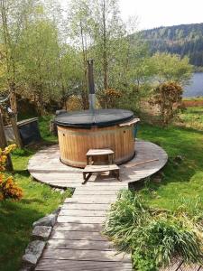 a wooden walkway with a hot tub and a bench at Red Kite Eco Bothy - with Hot Tub in Castle Douglas