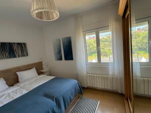a bedroom with a blue bed and two windows at Atalaya Luarca Apartamentos turísticos in Luarca