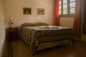 a bedroom with a bed with a blanket and a window at Hostería La Pergola in Villa Serranita