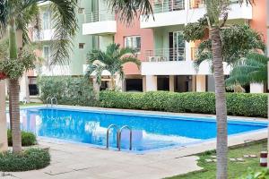 una piscina di fronte a un edificio con palme di The fabulous appt with pool in Virage Yoff Dakar a Dakar
