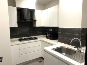 a white kitchen with a sink and a stove at Luxor Apartments & Suites - Opus in Lahore