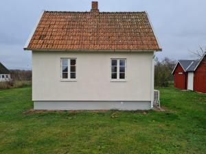 a white house with an orange roof in a yard at Litet mysigt hus i Östra Göinge in Västraby