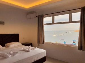 特鲁卡那拉特New Anugrah Hotel的一间卧室，有一扇大窗户，可以看到海景